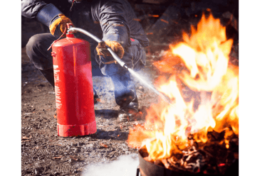 Using a fire extinguisher to fight fire. Blazing fire, the fire extinguisher at an angle aiming directly towards the fire.