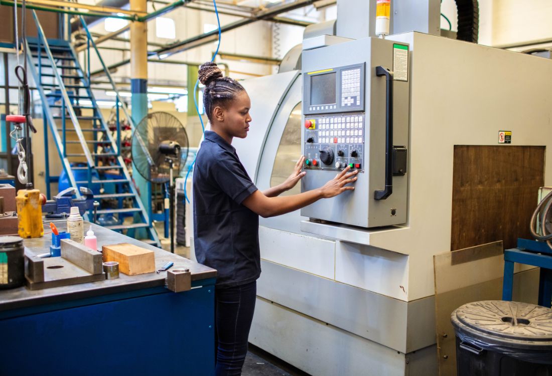 A CNC machine operator starting up her production line and being kept safe by the fire suppression system installed inside that reacts automatically to high temperature to safeguard workers and minimise downtime